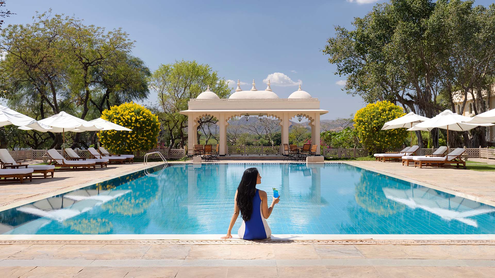 Guest relaxing near swimming pool at Trident Udaipur, a 5 star hotel in Udaipur with serene poolside experiences.